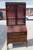 A bureau bookcase, the top having twin glazed doors opening to reveal shelves within,