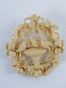 An antique ivory brooch featuring doves upon a recency urn in ivy leaf frame, 5.5cm dia.