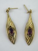 A pair of yellow metal earrings having central oval cut amethysts, no apparent hallmarks, 2.1g.