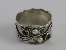 A handmade white metal ring set with garnet cabachons and seed pearls in the Arts and Crafts style