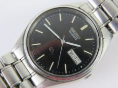 A Seiko SQ stainless steel wristwatch with original strap, black dial with day and date apertures.