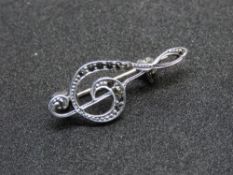 An Art Deco style silver and marcasite music themed brooch in the form of a treble clef.
