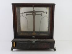 A set of jeweller's scales in glazed display case with drawer under. Case 38cm wide.