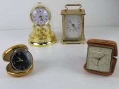 A Smiths Empire travel clock together with another travel clock and two small mantel clocks.