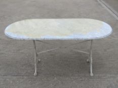 A cast metal and marble oval garden table, marble having old removable protective film upon,
