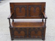 A c 1930s oak fold over monks bench, seat lifting to reveal compartment within, 106 x 102 x 52cm.