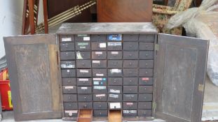 A two door cabinet opening to reveal 60 micro drawers within, all having turned drawer handles,