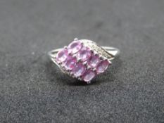 A 9ct white gold and pink sapphire ring, eight oval cut faceted stones in claw settings,