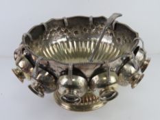 A large and impressive silver plated punch bowl with eleven cups and associated punch ladle,