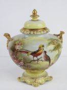 A 19thC Royal Bonn twin handled lidded urn decorated with exotic birds in a floral setting with
