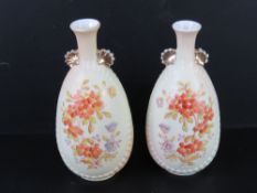 A pair of blush ground vases having floral decoration upon and standing 22cm high. One slightly a/f.