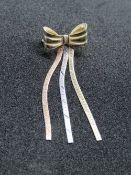 A 9ct gold tri-colour brooch in the form of a bow with ribbons, hallmarked 375, 1.3g.