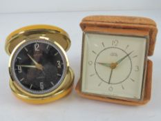 A Smiths Empire travel clock together with another travel clock and two small mantel clocks.