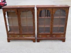 A matched pair of contemporary walnut quarter veneered twin door glazed bookcases having twin