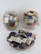 A large collection of match books within two large glasses and a Continental serving dish.