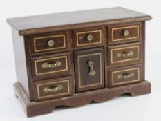 A contemporary wooden jewellery box having lift up lid and various drawers under.