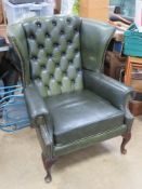 A green upholstered wing back arm chair approx 82cm wide, 1m high at back.