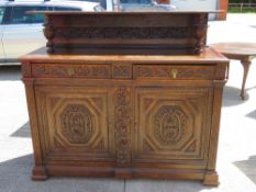 A late Victorian carved oak court cupboard having twin drawers with doors under,