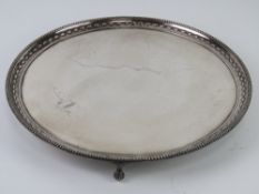 A large English made heavily silver plated circular serving tray raised over three ball and claw