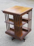 A large revolving late Victorian Canterbury bookcase raised over quatreform base terminating in