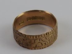 A 9ct gold wide band having engraved foliate decoration upon, hallmarked 375, size P, 4g.