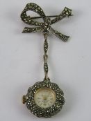 A silver and marcasite watch suspended from a brooch in the form of a bow, London import hallmark,