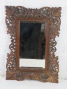 A Black Forest type carved wooden frame, good bevelled edge mirror within. Overall 37 x 52cm.