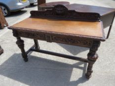 A late Victorian carved oak buffet or side table having twin frieze drawers with Green Man