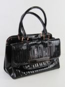 A black patent handbag by Ted Baker approx 34cm wide, some wear noted.