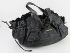 A black leather handbag marked for Miu Miu, unauthenticated, having purple satin type lining,