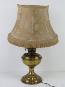 A brass oil lamp having been converted for use as an electric table lamp,