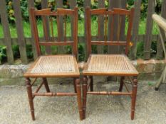 A matched pair of cane seated bedroom chairs having architectural pediment backs, ring turned legs.