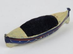 A pin cushion being a painted metal Royal National Lifeboat Institution boat, 10cm in length.
