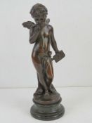A bronzed metal figurine of a winged cherub with envelope in hand, raised over marble base, all