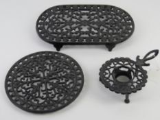 Three contemporary cast iron and painted trivets of various forms.