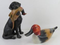 A hand made and painted wooden duck 41cm in length together with a figurine of a black Labrador with