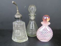 A Sterling silver and cut glass perfume bottle together with two other glass bottles. Three items.