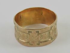 A yellow metal wide band having 3/4 floral engraving, no apparent hallmark, size Q, 3.1g.