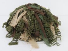 A 1977 British Brodie helmet with liner and camo netting.