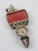 A large silver pendant having floral mother of pearl, green coloured pearl and faceted stones upon,