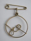 A vintage yellow metal brooch 'G' within circle suspended below safety pin style bar, 2.7cm wide.