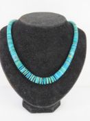 A Native American turquoise beaded necklace having white metal ends with engraved pattern upon