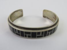 To match above lot. A Sterling Silver Native American black onyx geometric pattern bangle marked