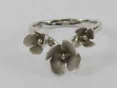 A silver floral ring having trio of flower buds on a wishbone band, stamped 925 with designers mark,