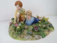 A Crown Staffordshire figurine of two children in a garden, modelled by T. Bayley.