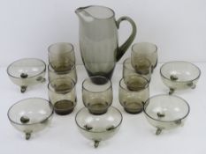 A 1960s smoked glass breakfast set comprising jug, seven glasses and five bowls.