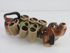 An unusual Japanese Brandy dog in the form of Daschund having six basket design cups upon,