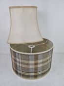 Two lampshades, one being cream silk, the other in tartan pattern.