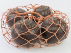 Four lignum vitae balls / boule in string carry bag.