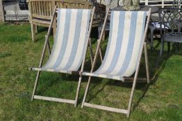 A pair of wooden framed deck chairs.